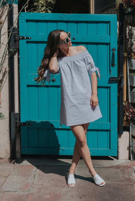Jeune femme en robe devant une porte bleue