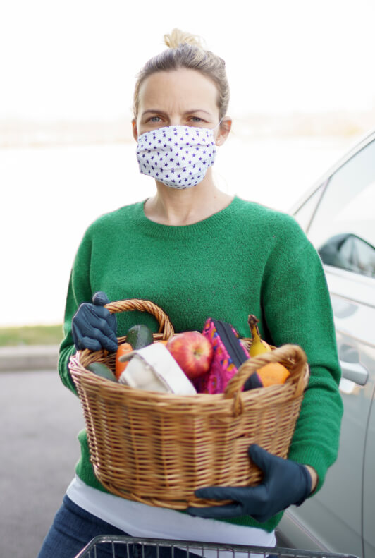 Femme en masque et gants avec panier de courses